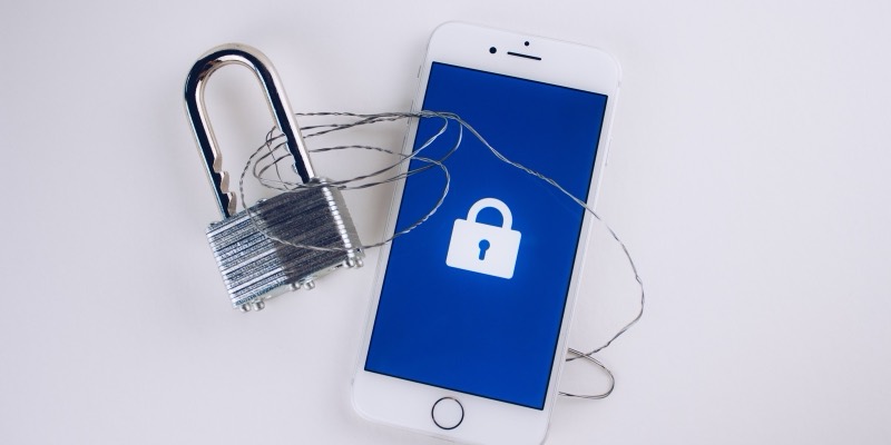 A metal padlock wrapped in wire next to an iPhone showing a lock icon on its screen