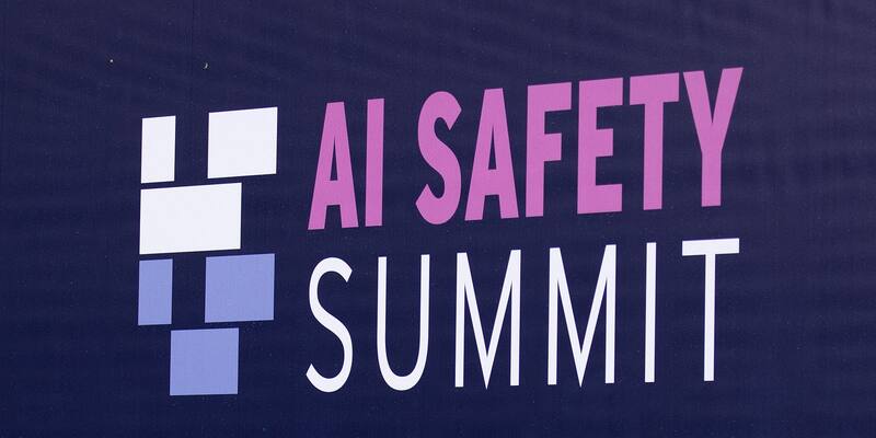 The AI Safety Summit logo in pink and white on a navy sign at Bletchley Park