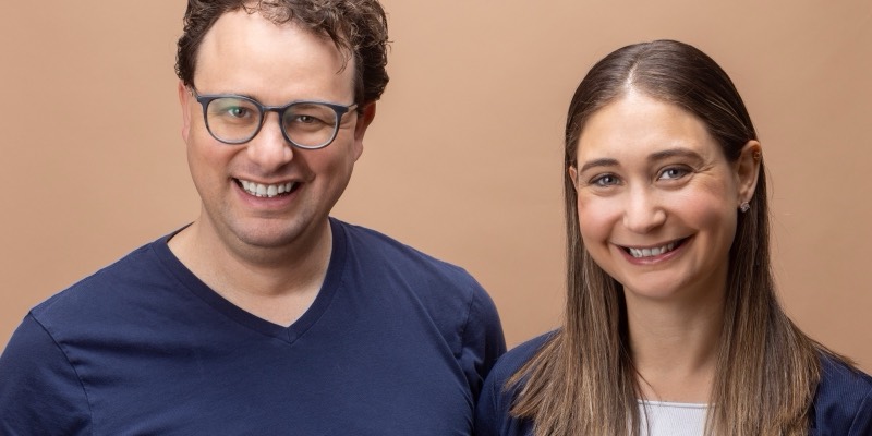 Anthropic CEO Dario Amodei, in glasses and a navy T-shirt, and his sister Daniela Amodei, Anthropic's president, smiling in front of a plain tan background