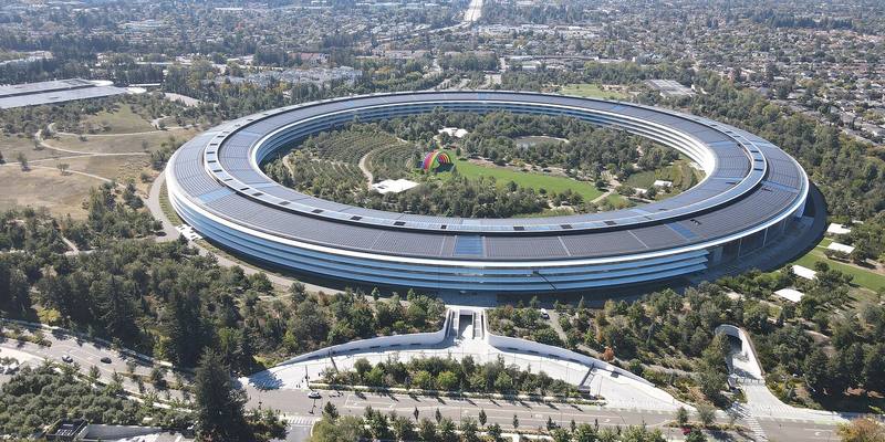Aerial view of Apple Park, a huge ring-shaped building surrounded by trees, in Cupertino, California.