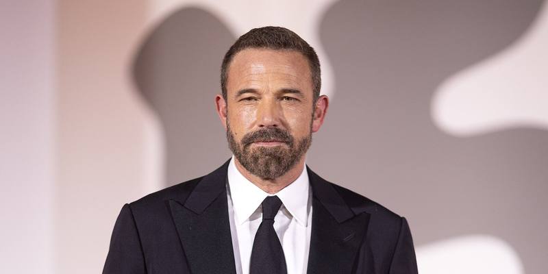 Ben Affleck, bearded, in a black suit and tie on the red carpet at the Venice Film Festival.