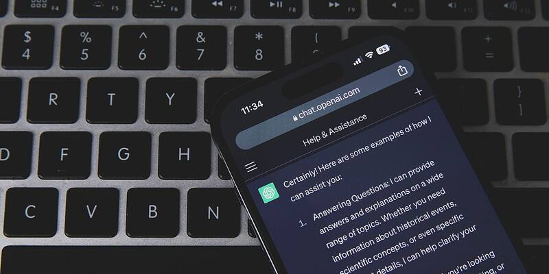 A smartphone showing a ChatGPT conversation in a browser, lying at an angle on a dark laptop keyboard.