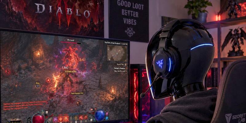 Illustration of a white and black Tesla Optimus robot wearing a gaming headset, playing Diablo IV at a desk with a glowing monitor