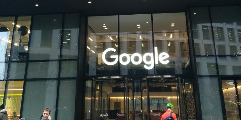 The glass entrance of Google’s building at 6 Pancras Square in London, with a large illuminated Google sign