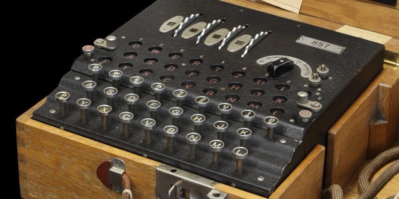 Close-up of an Enigma cipher machine in its wooden case, showing the rotor windows, lamp board and keyboard