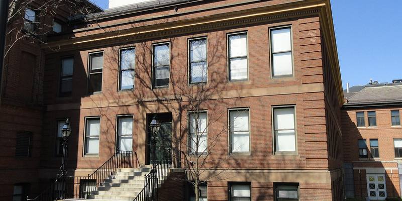 A red-brick Harvard physics laboratory building with stone steps and bare trees under a blue sky.