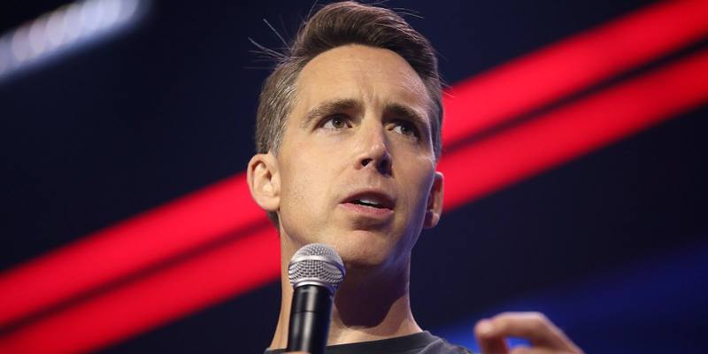 Senator Josh Hawley speaking into a microphone in front of red and blue stage lights