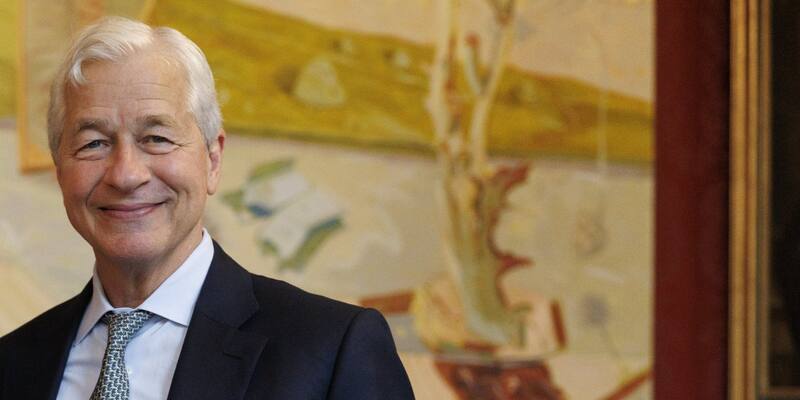 Jamie Dimon, grey-haired and smiling, in a dark suit and patterned tie in front of a large painting
