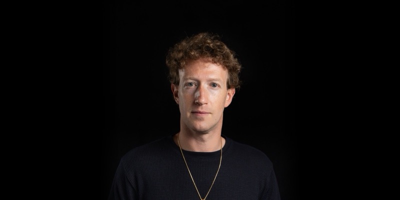 Mark Zuckerberg in a black top and gold chain against a black background