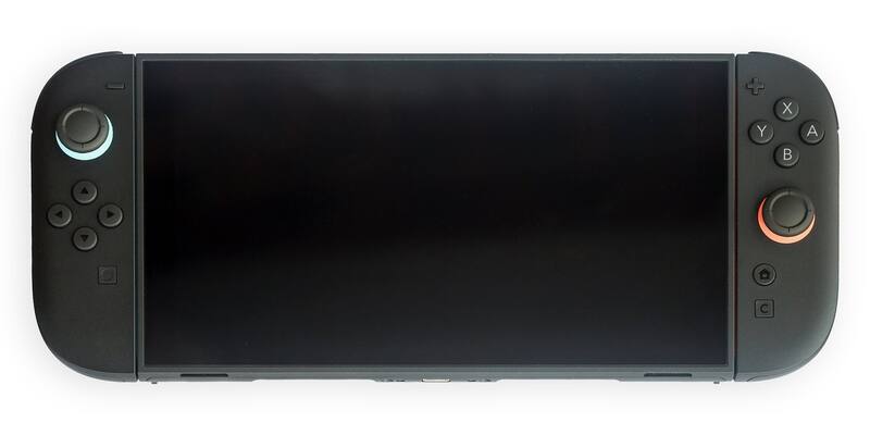 A black Nintendo Switch 2 console in handheld mode with its Joy-Con 2 controllers attached, blue and orange rings around the sticks, on a white background