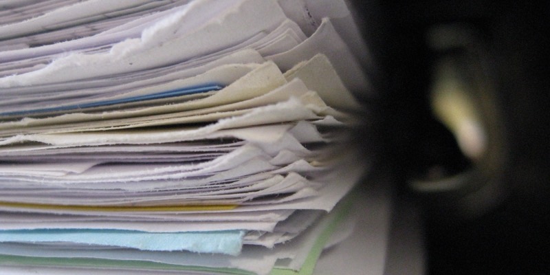 A thick, messy stack of paper documents seen side-on