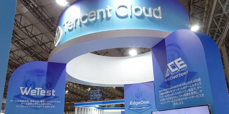 A large curved blue Tencent Cloud sign above an exhibition stand, with WeTest, EdgeOne and Anti-Cheat Expert panels below